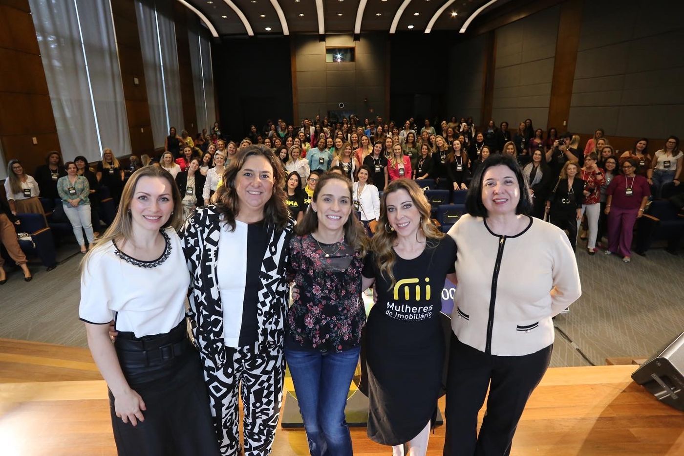 Integrantes do IMI no palco diante de um auditório lotado