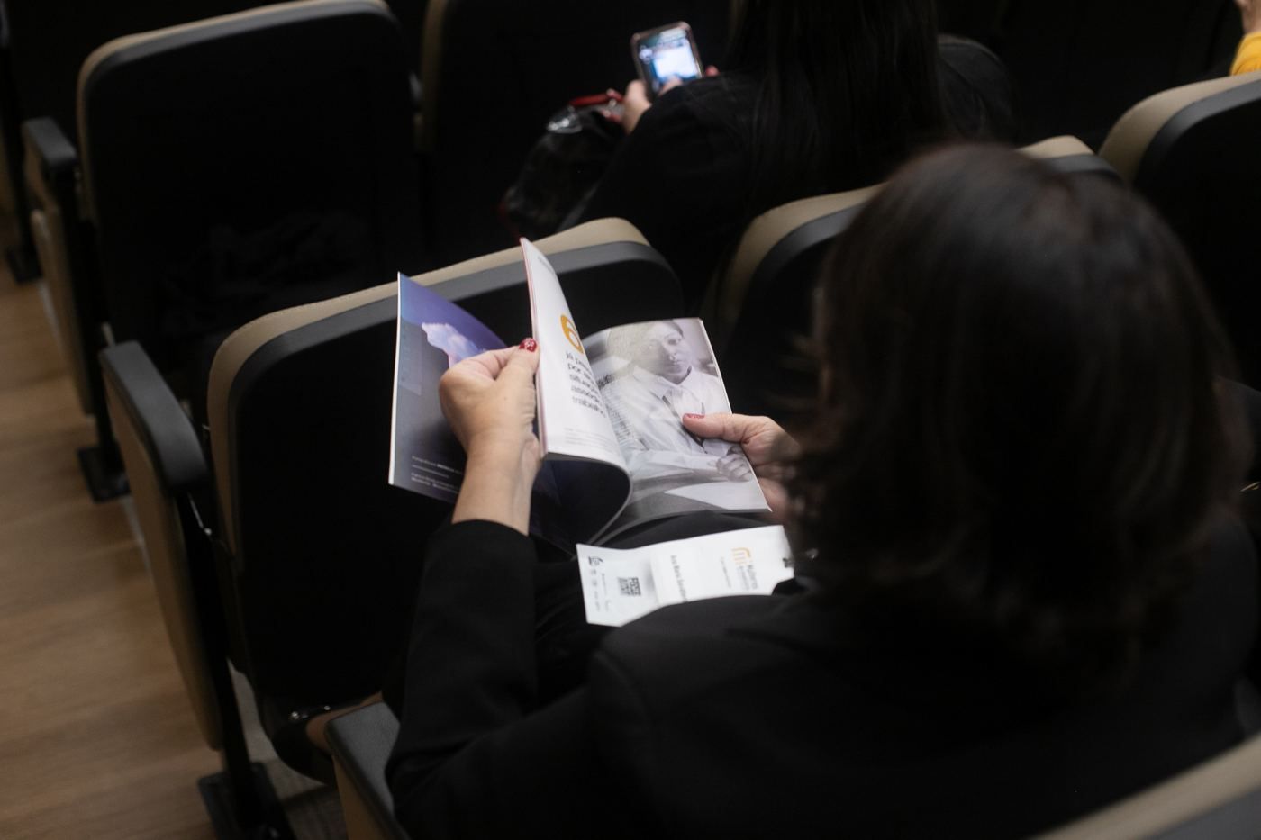 Leitora folheando a revista comemorativa durante a celebração